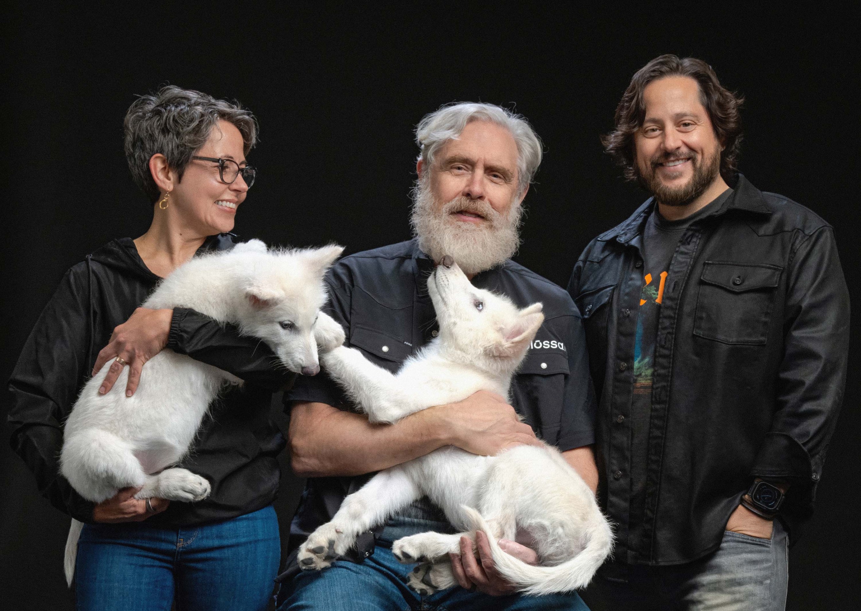 Ben, Beth, and George of Colossal Biosciences pose with dire wolf pups.