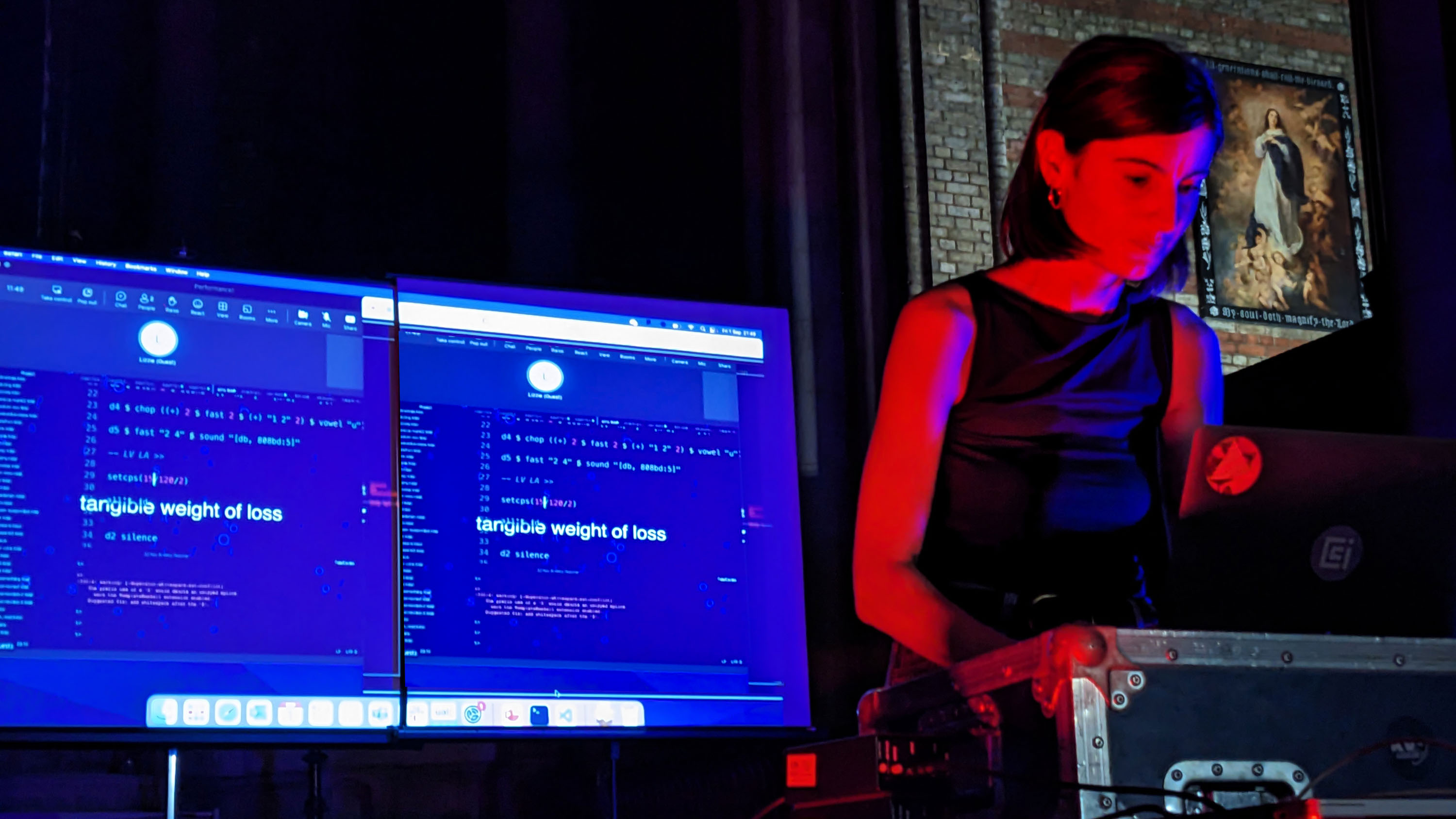 person standing in colored party lights at a table with a computer display behind them