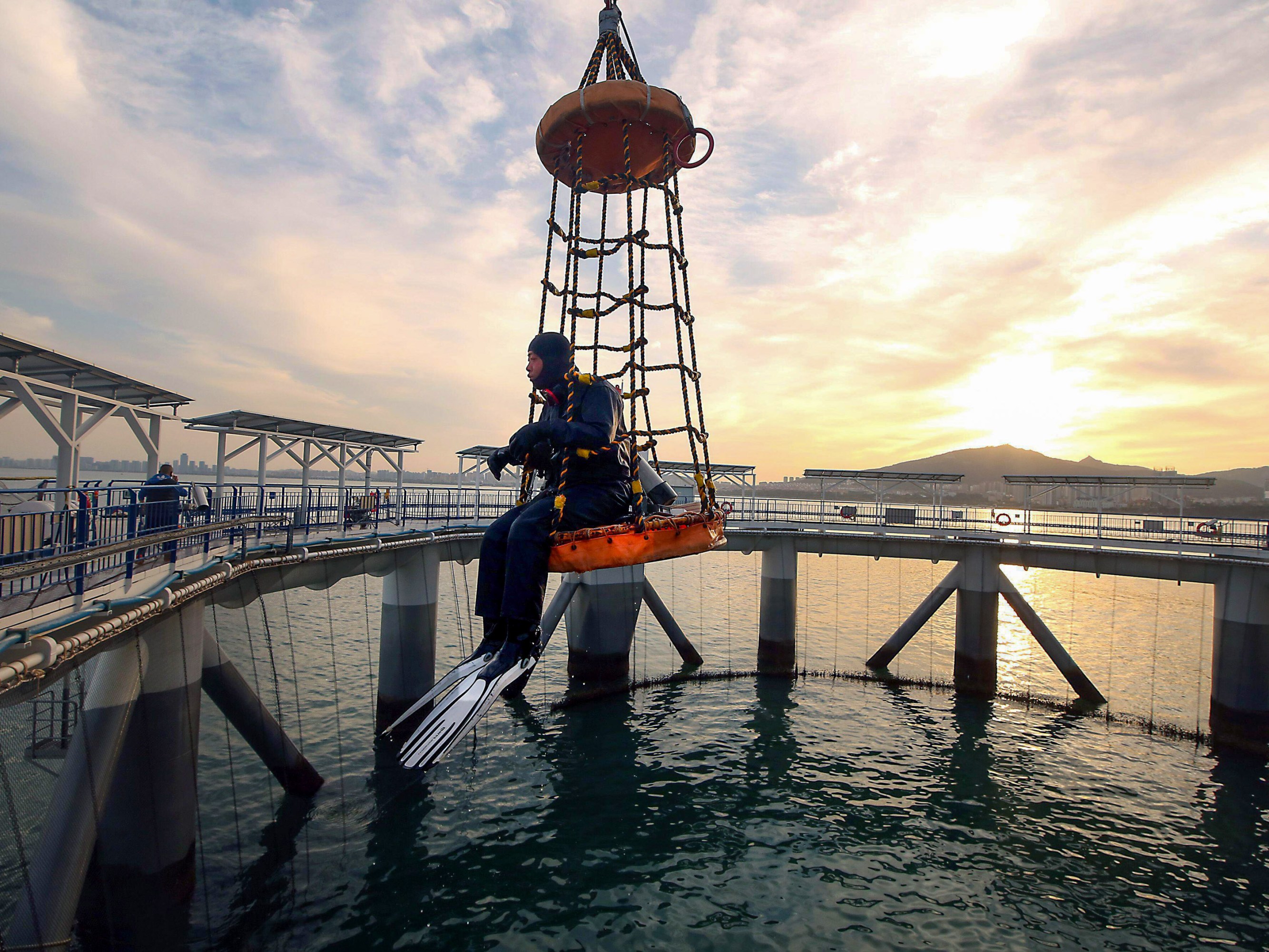 a person in a wetsuit at sunset sitting in a net