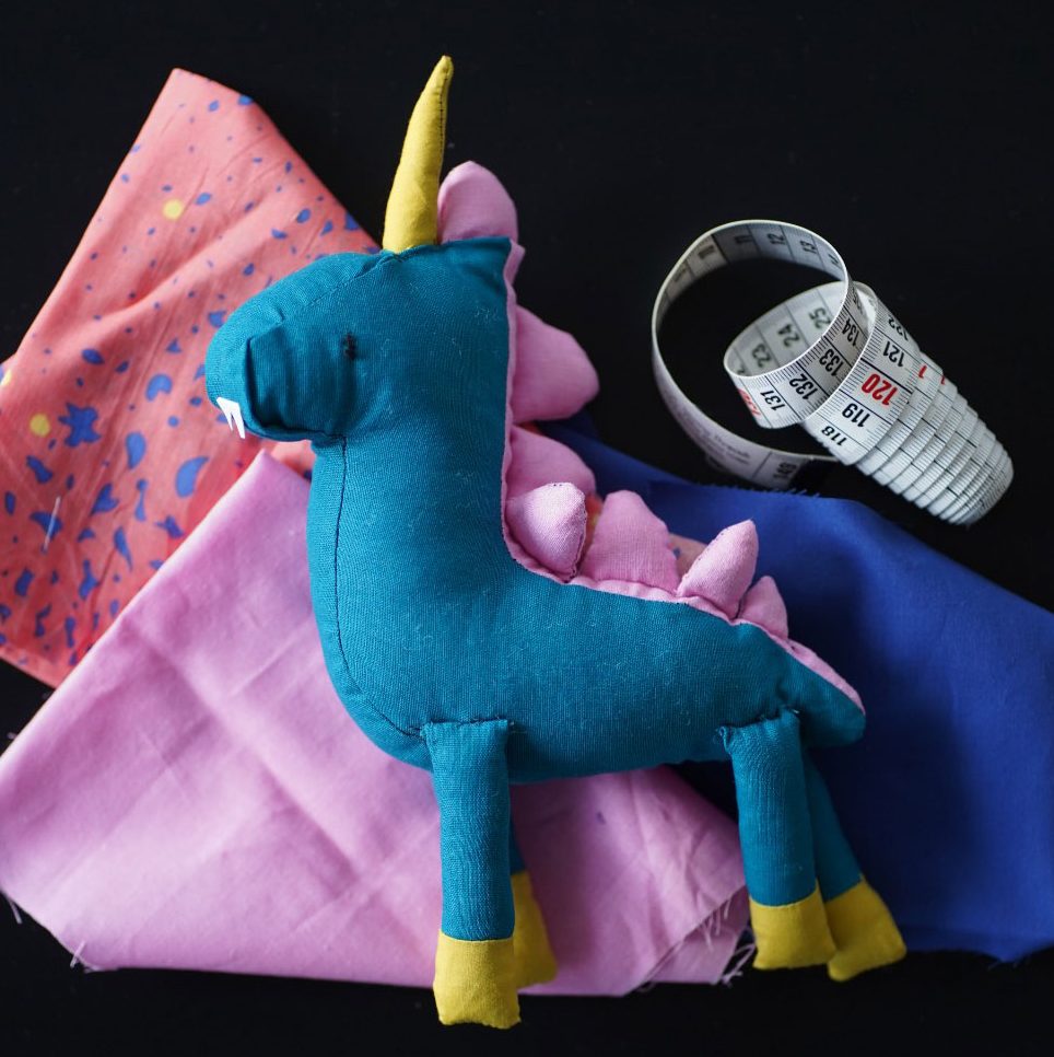 a stuffed unicorn and sewing materials